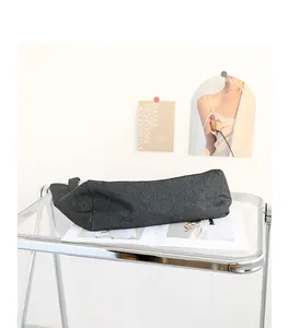 Detalle lateral de un bolso tote de lona vaquera gris oscuro sobre soporte acrílico