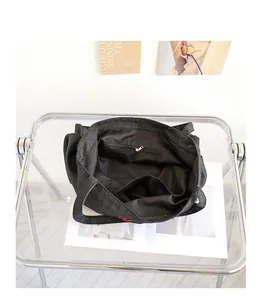 Detalle del interior espacioso del bolso tote de mezclilla negra con bolsillos.
