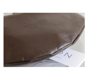 Primer plano de la textura de cuero PU suave marrón oscuro de un elegante bolso dumpling.