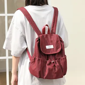Mochila vintage de lona roja con cierre de cordón y textura de mezclilla plisada para mujer