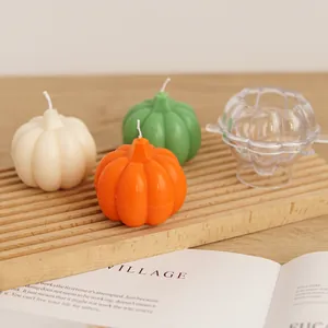 Close-up of a clear acrylic pumpkin candle mold shown with finished candles on wood