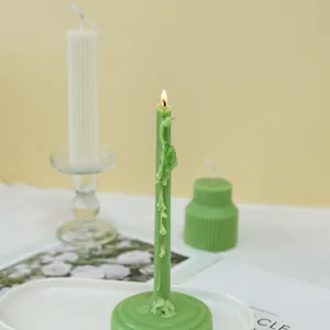 Close-up of a decorative light green taper candle with wide base and melting wax effect