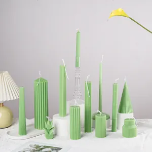 Green fluted and geometric scented candles arranged on white minimalist display pedestals.