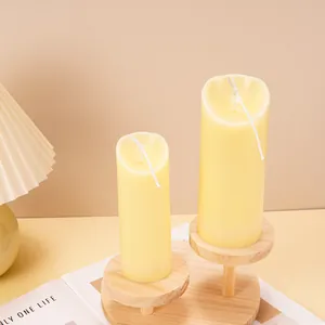 Detail view of two creamy yellow wavy-top pillar candles placed on a rustic wooden stand