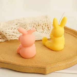 Vue macro de jolies bougies de lapin roses et jaunes sur un plateau en céramique rustique.