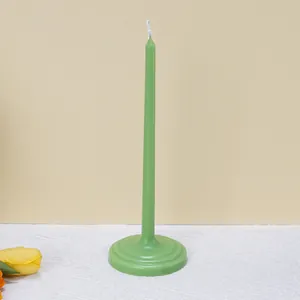 Detail view of a green aromatherapy taper candle with a wide circular base on a white cloth