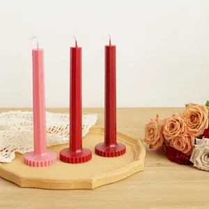 Detail view of elegant geometric taper candles with unique ribbed base in pink and red tones