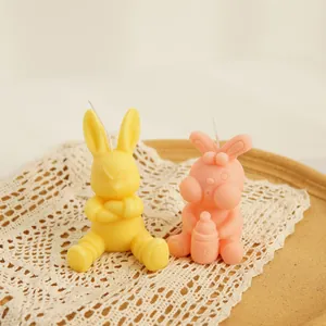 Bougies parfumées en forme de lapin en jaune et rose sur un napperon en dentelle et plateau