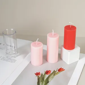 Close-up of DIY cylindrical plastic candle mold with finished pink and red candles.