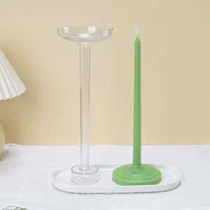 Close-up of a clear plastic taper candle mold and finished green candle on a tray