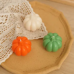 Macro view of detailed pumpkin-shaped scented candles in white orange and green colors