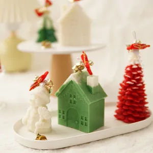 Close-up of festive Christmas scented candles featuring snowman, green house and red tree