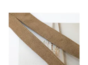 Close-up detail of a durable brown canvas bag strap with fine stitching and weave texture