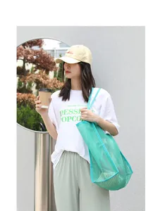 Bolso tote de malla verde de estilo coreano informal llevado por una modelo al aire libre