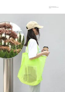 Modelo con bolso de malla verde neón frente a una pared gris de estilo minimalista