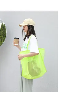 Vista detallada de un bolso de malla verde neón llevado por una modelo al aire libre