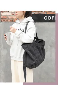 Female model wearing a white hoodie carrying a large black canvas tote bag outdoors