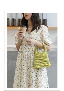Asiatisches Model hält die gelbe handgewebte Netztasche in einem gemütlichen Café-Ambiente