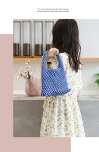 Detailansicht der blauen handgewebten Baumwolltasche, getragen von einem Modell im Blumenkleid
