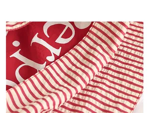 Detailed macro view of a red nylon tote bag featuring white letters and red striped patterns.