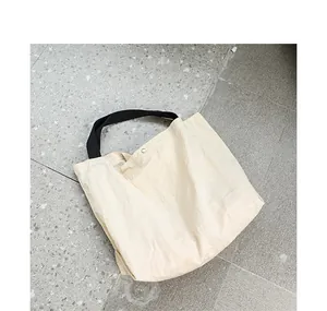 Dettaglio della borsa tote in nylon beige con spalline nere e bottone a pressione