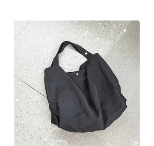 Vista dettagliata di una grande borsa tote in nylon nero impermeabile con bottone a pressione