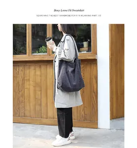 Detail of large dark grey corduroy tote bag carried by model in casual street scene.