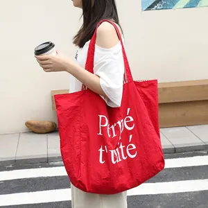 Stylish large red nylon tote bag featuring white Perpétuité letter print on urban street background