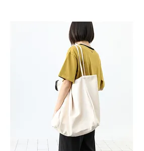 Detailed view of a large cream washed canvas tote bag worn by a model