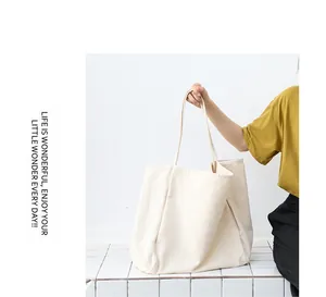 Large off-white washed canvas tote bag held by a model for size and style detail.
