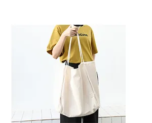 Large capacity beige canvas tote bag shown with model in a casual and minimalist setting