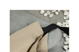 Vista dettagliata delle cuciture rinforzate e del tessuto in nylon impermeabile beige della borsa.