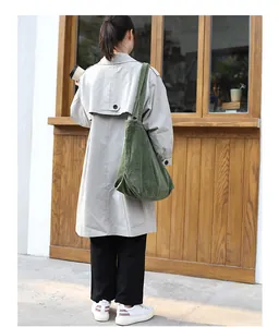 Full length back view of woman wearing a trench coat carrying olive green corduroy tote bag