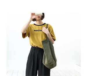 Model showcasing a large olive green washed canvas tote bag in a minimalist setting