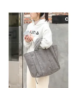 Detailed shot of a large grey washed canvas tote bag worn by a model in casual street style