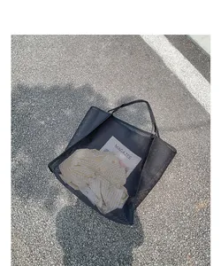 Primer plano de bolsa de malla negra sobre asfalto que muestra la textura calada.