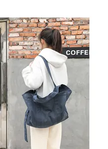Detailed view of dark blue washed canvas tote bag worn by a model in casual setting.