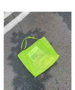 Bolso de malla verde neón con diseño minimalista transparente sobre fondo de asfalto