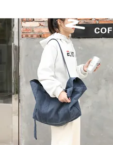 Model carrying a large navy blue canvas tote bag in a casual city street setting