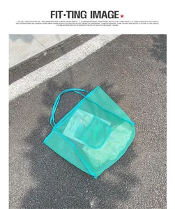 Vista detallada de un bolso de malla turquesa sobre asfalto, destacando la textura.