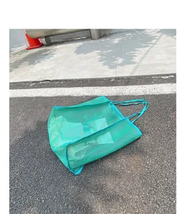 Vista de estilo de vida al aire libre de un bolso de malla verde sobre asfalto