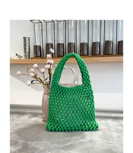 Handgewebte grüne Netztasche aus Baumwollkordel in einer modernen Café-Umgebung.