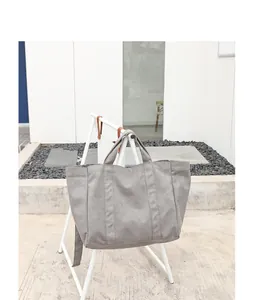 Large grey washed canvas tote bag for women shown hanging on a minimalist white metal stand
