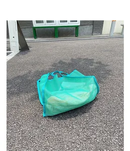 Vista detallada de un bolso de malla turquesa descansando sobre una superficie de asfalto.