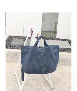 Navy blue washed canvas tote bag hanging on a white minimalist display stand for a casual look