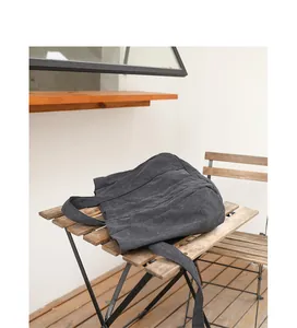 Dark grey washed canvas shoulder bag placed on a rustic wooden table.
