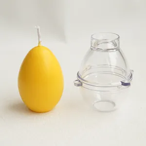 Detail showing a clear egg-shaped plastic candle mold and a finished yellow wax egg