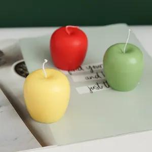 A macro detail view of three realistic apple-shaped scented candles on a stylish magazine