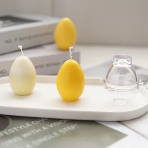 Detailed view of egg-shaped candle set and clear plastic mold on a white tray