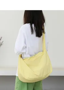 Pale yellow nylon shoulder bag shown as a minimalist crossbody detail on a model